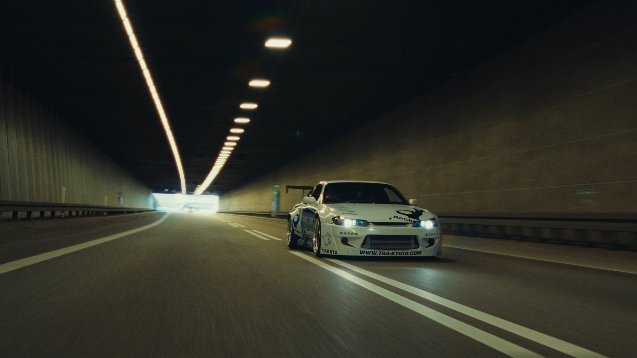 Halation off versus on at 35mm: a drift car in a tunnel, the ceiling light strip and headlights bleeding into the dark