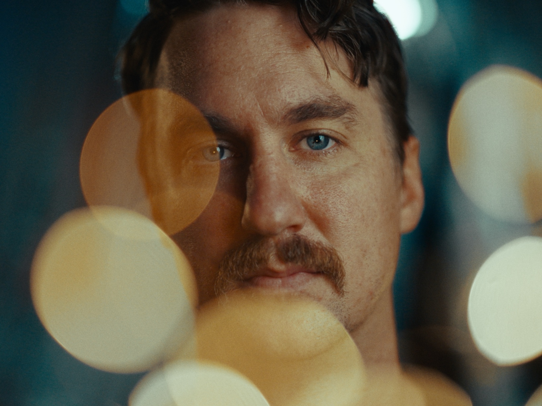 A portrait rendered through an EMBR-built negative: warm skin against a teal background, with large out-of-focus highlights across the frame.